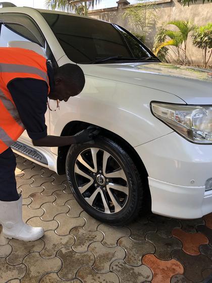 Detailer dressing the tyre of a white Toyota Land Cruiser V8 in a Runda driveway