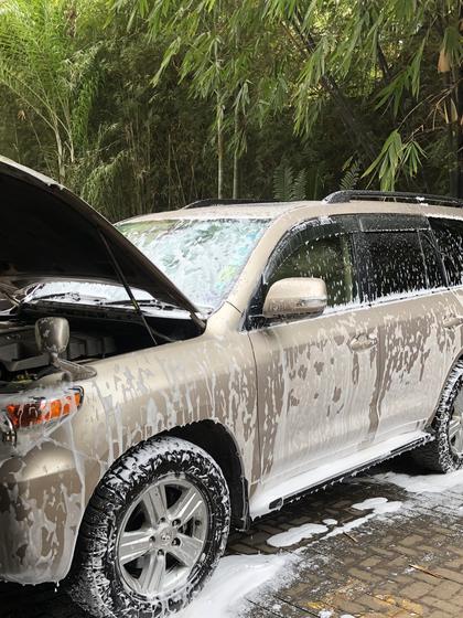 Gold Toyota Land Cruiser covered in snow foam with the bonnet open