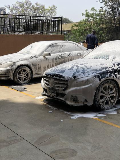 Two Mercedes-Benz saloons covered in snow foam in a car park