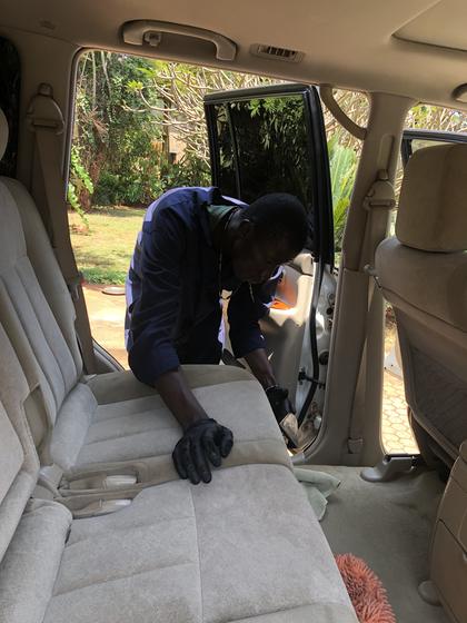Detailer shampooing the fabric rear seats of a Toyota Prado