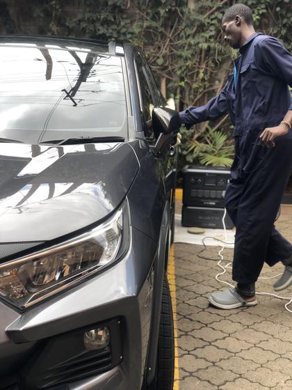 Detailer finishing a grey Toyota RAV4, with the team's portable power station behind him